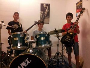 Un gruppo di giovani allievi nel classico trio rock chitarra, basso e batteria, durante una lezione presso la scuola Musictime di Milano